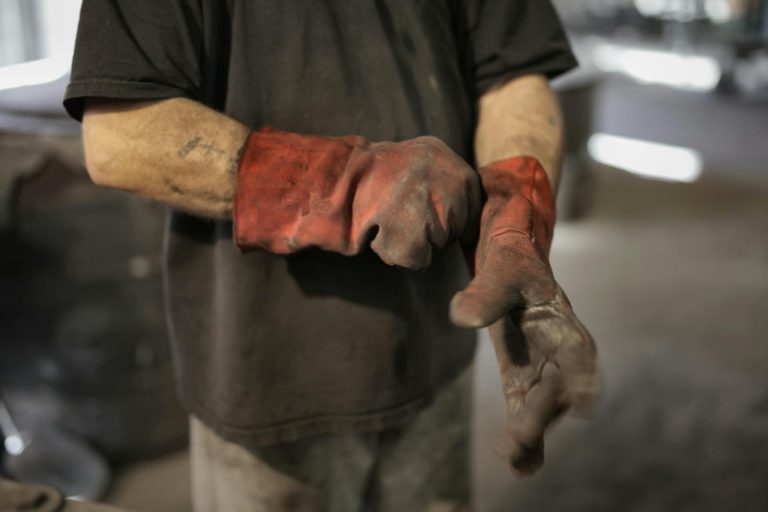 Ein Arbeiter zieht sich Schutzhandschuhe an